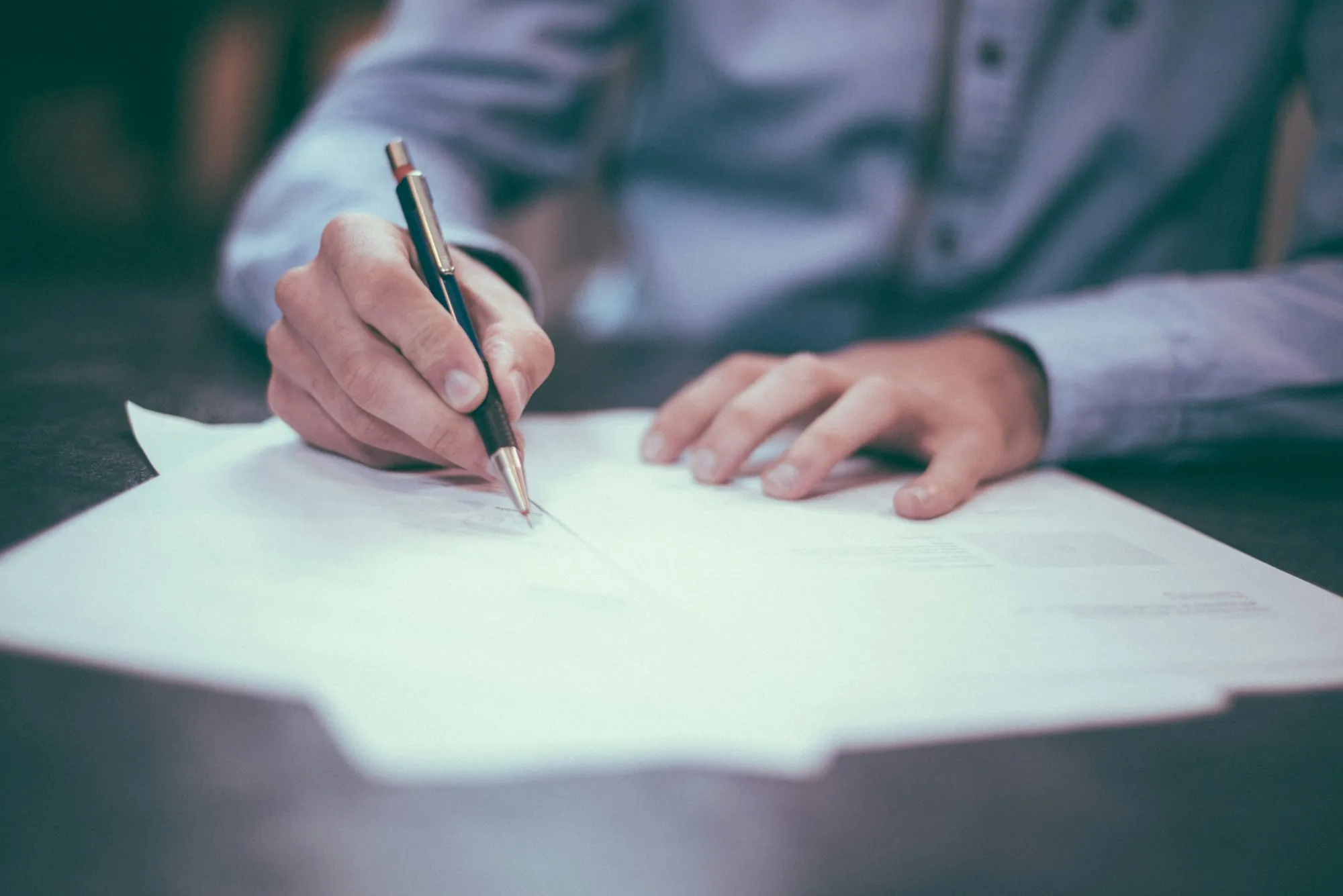 Hand signing a document with a pen, the kind of paperwork to review before solar panels come off a roof in Oak Forest
