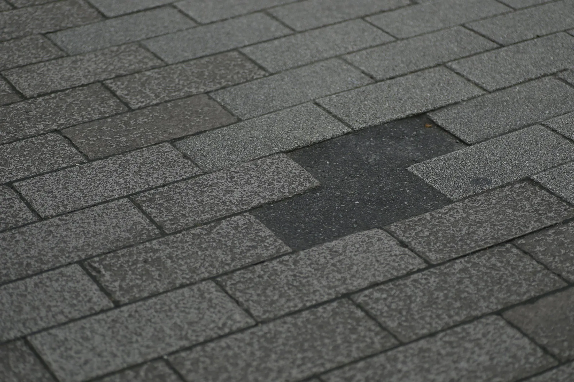Worn gray shingle roof with a patch of missing shingles