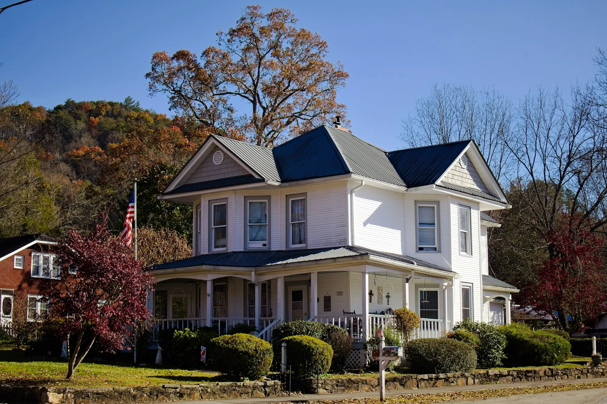 White Victorian-style house with a porch in autumn
