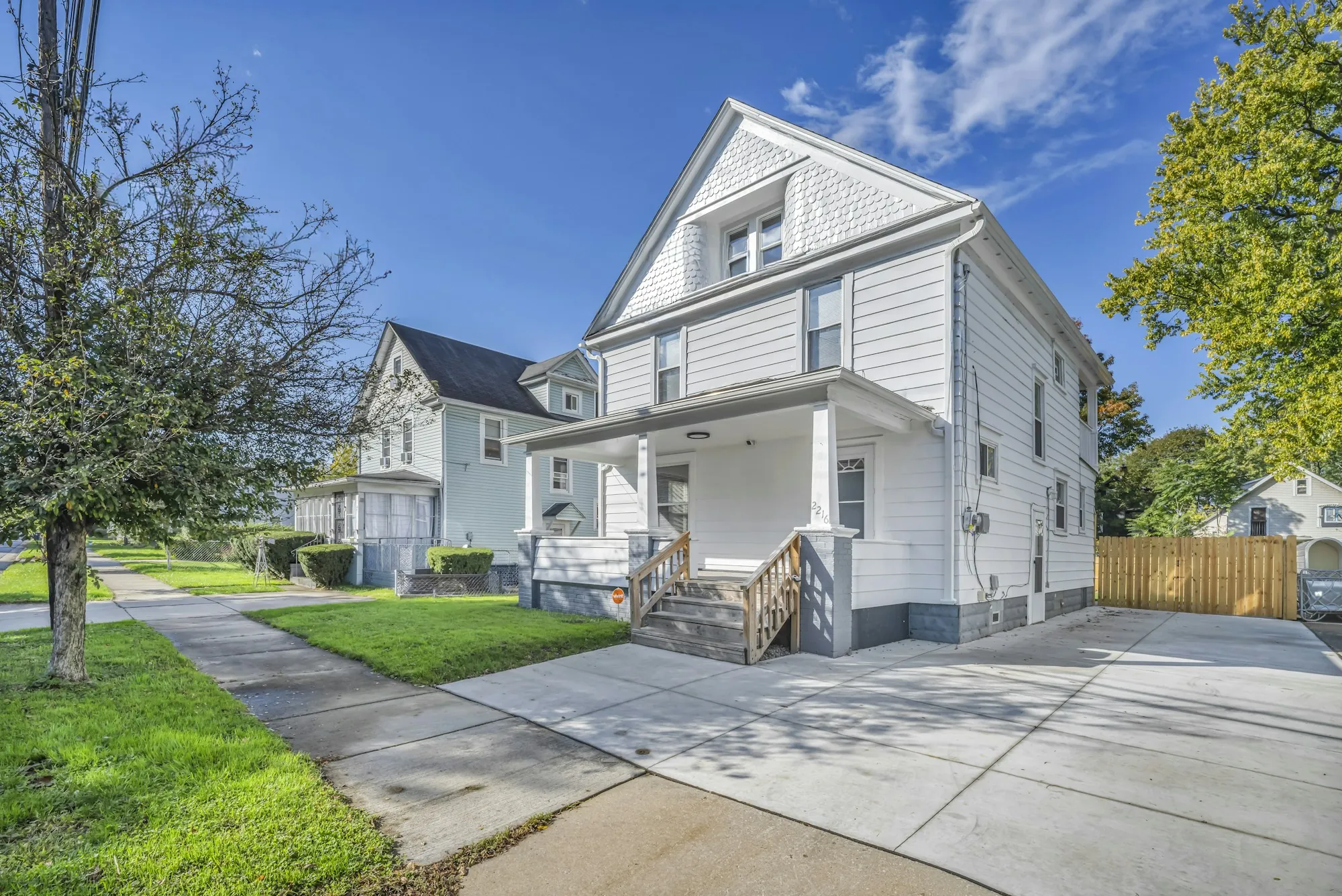 White two-story house with a front porch and concrete driveway