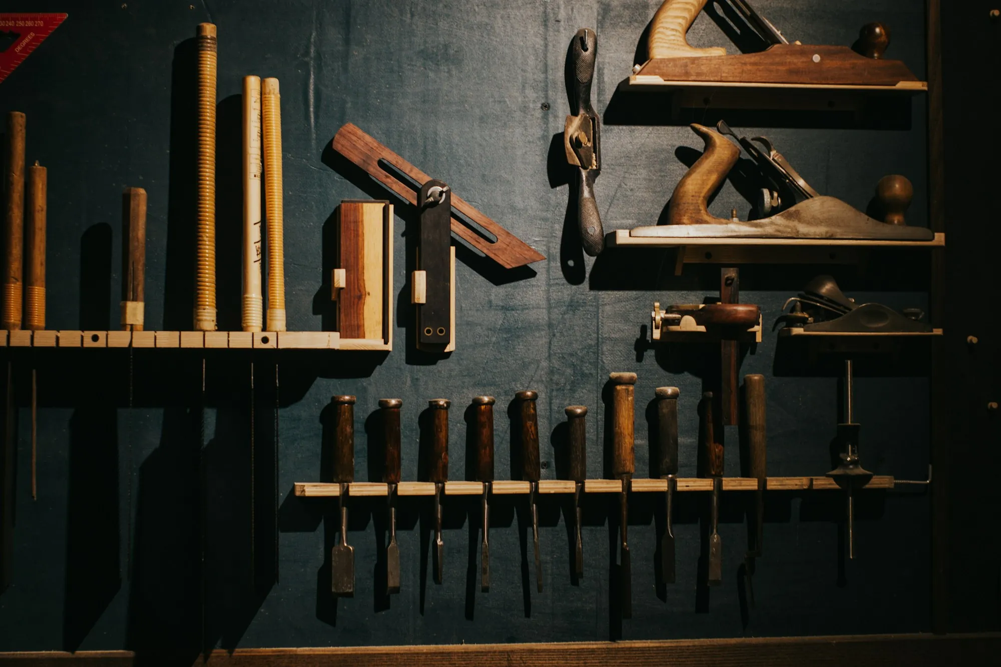 Woodworking tools hung neatly on a dark workshop wall